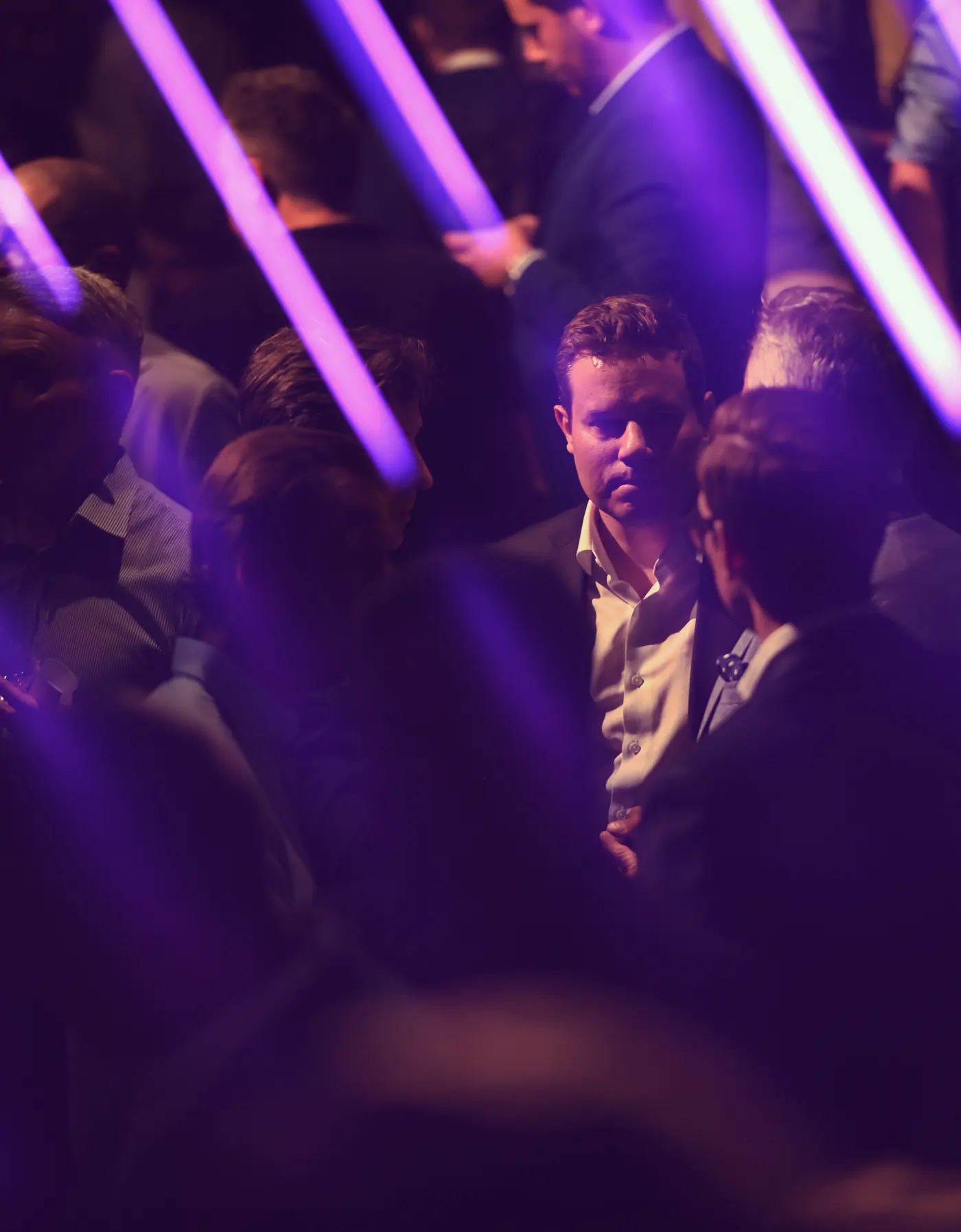 Guests in conversation at AssetRush, lit by purple light beams